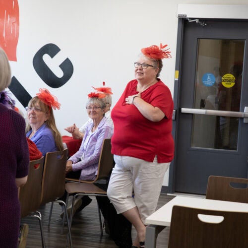A woman wearing a red hat speaks to students that are out of frame.
