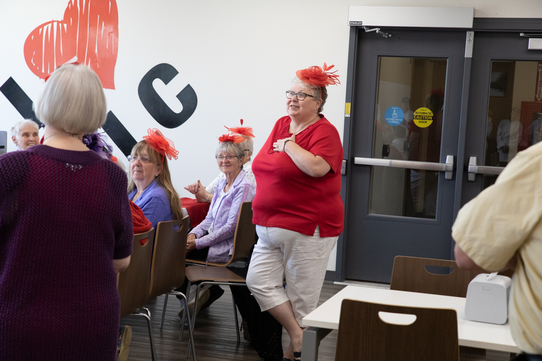 A woman wearing a red hat speaks to students that are out of frame.