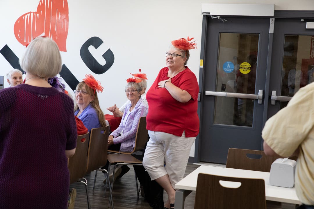 A woman wearing a red hat speaks to students that are out of frame.