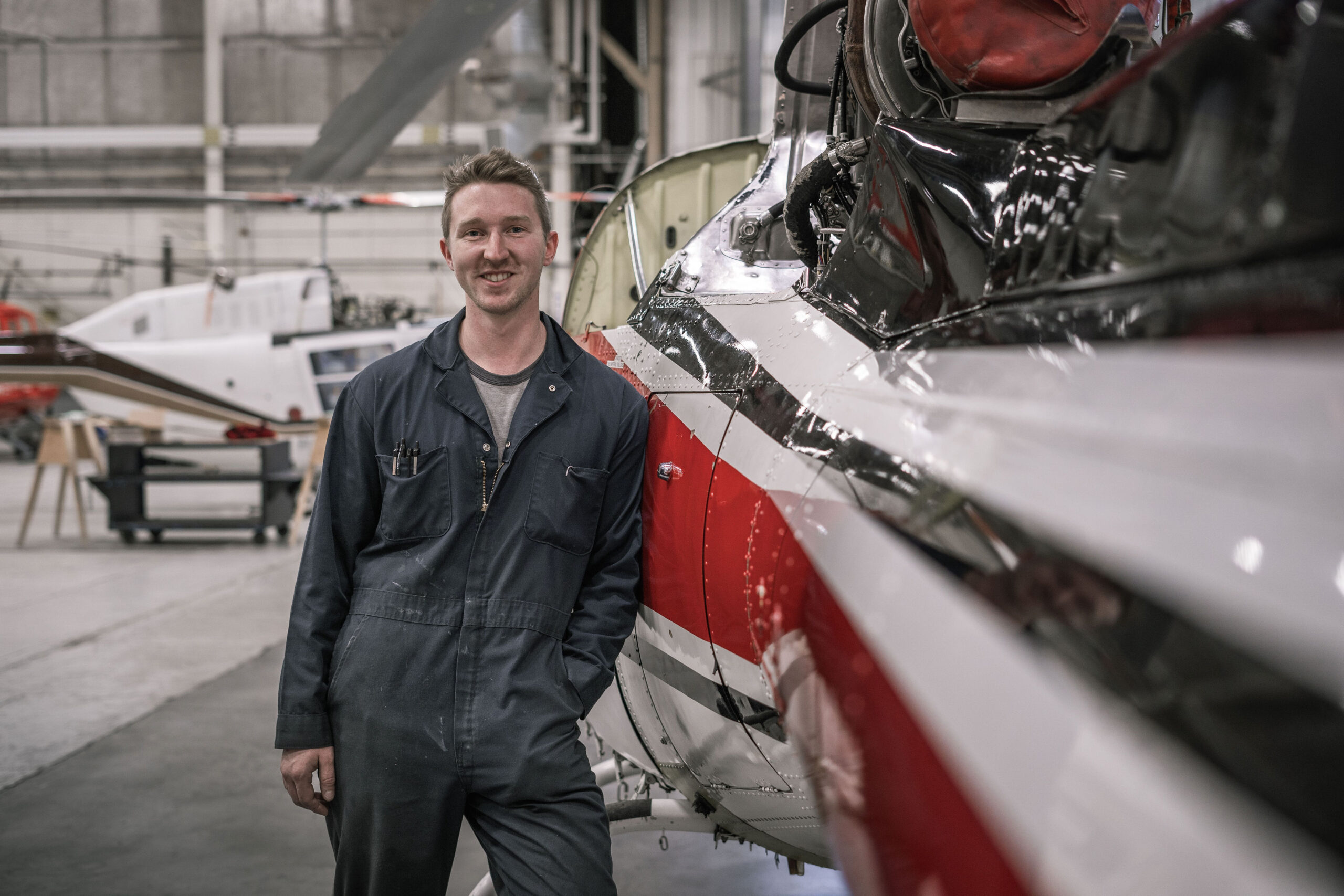 AMT student Bryce Brown stands next to a helicopter in the AMT hangar