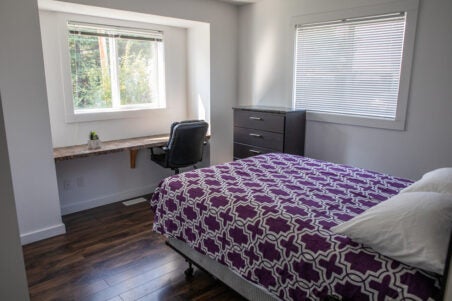 bedroom with 2 windows, chest of drawers, bed, desk and chair
