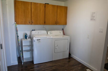 shelving unit, washer and dryer below cupboards