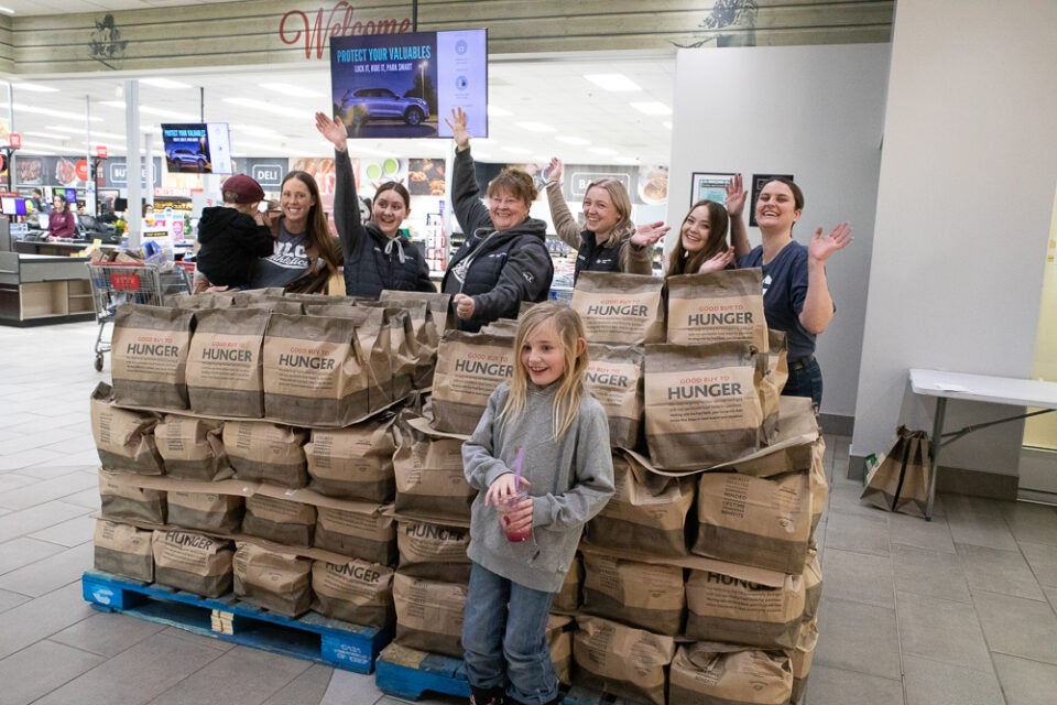A group stands around some packed brown paper bags