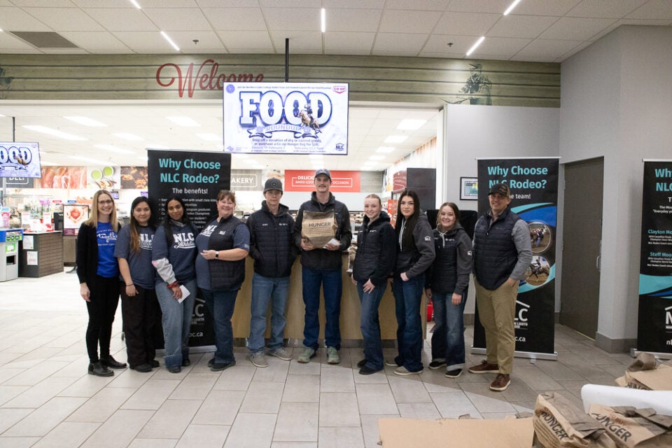 Students and staff stand in a line smiling for the camera