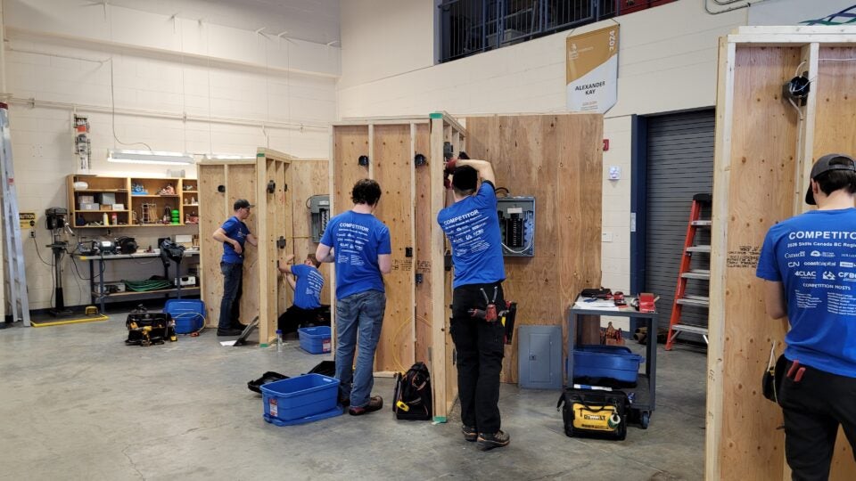 Students set up electrical setups on a wall