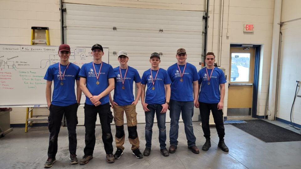 trades students stand in a line wearing medals