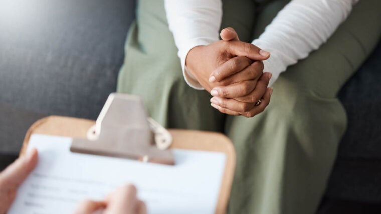 Woman, hands and therapist writing on clipboard in consultation for mental health, psychology or healthcare. Hand of female person or psychologist consulting patient with anxiety or stress in therapy.