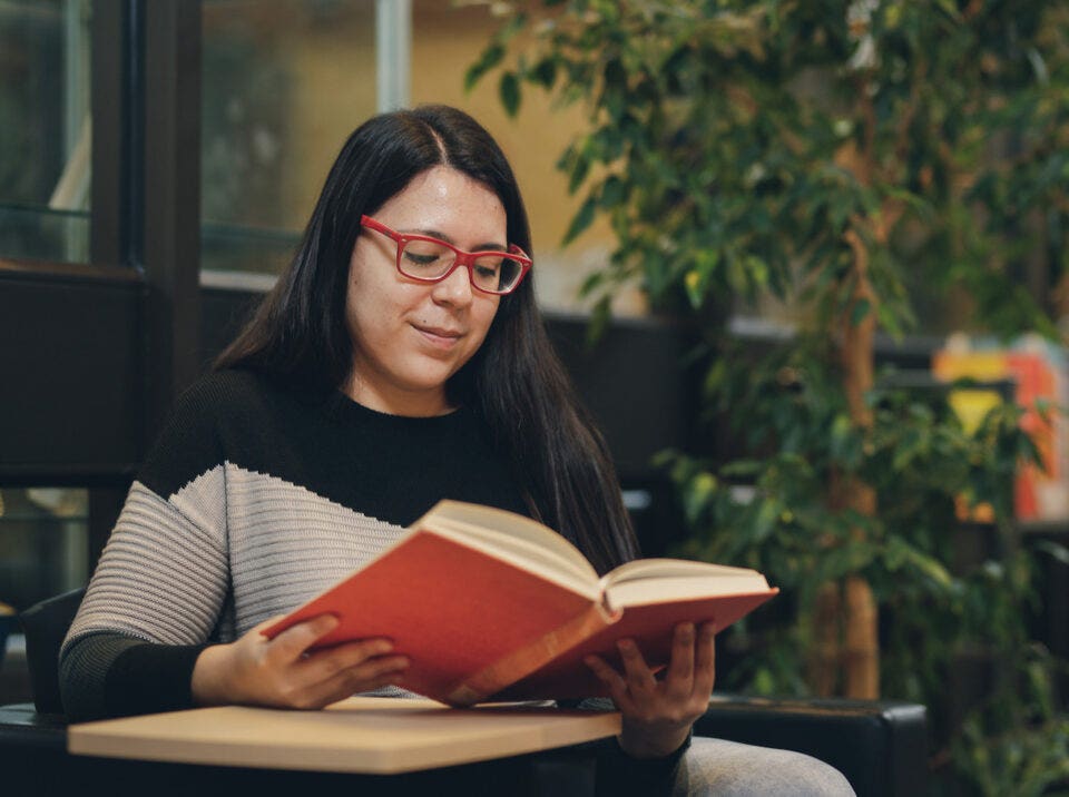 NLC student on campus reading a book